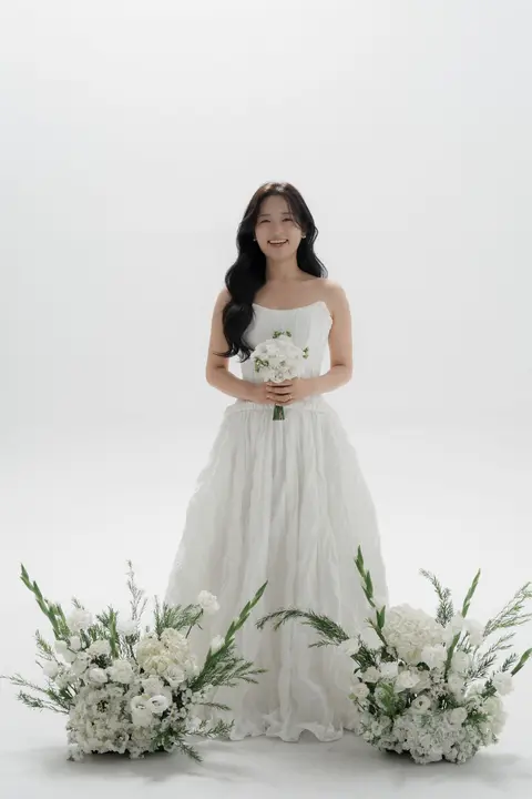 흰 꽃 사이에 서서 작은 부케를 든 신부