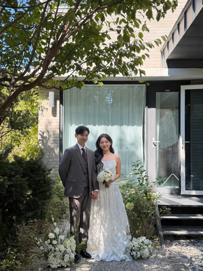 집 앞에서 손을 잡고 선 두 사람
