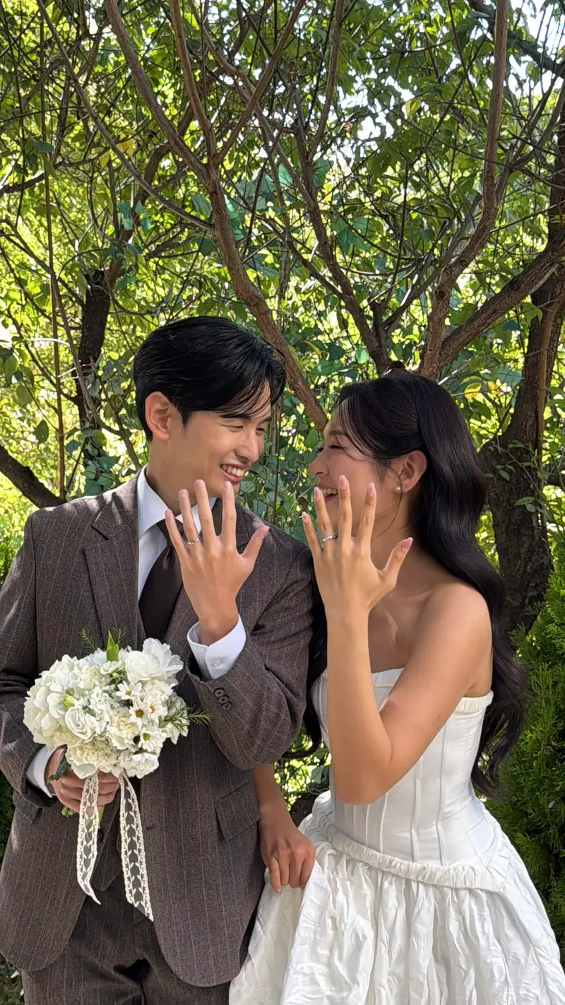 반지 낀 손을 서로 보여 주며 웃는 두 사람