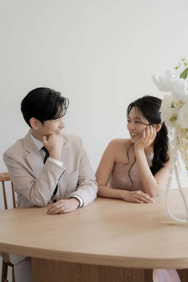 나무 탁자에 마주 앉아 웃는 두 사람