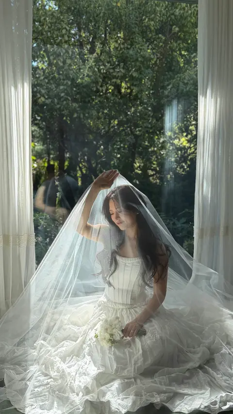 창가에 앉아 베일을 들어 올리는 신부